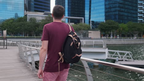 hombre caminando a lo largo del puente frente al mar en la ciudad