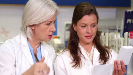 pharmacists maintaining a record of medicine on clipboard