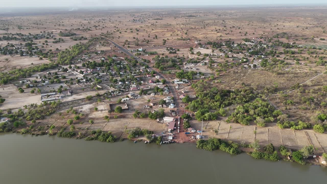 Drone shot of a village along the Gambia River with traditional houses and tropical vegetation on the riverbanks