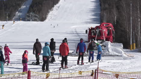 afeitadora de nieve roja remolcando a un grupo de esquiadores hacia una pista de esquí,chequia