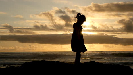 Silhouette-Eines-Mädchens-Im-Sommerkleid,-Das-Gegen-Den-Goldenen-Sonnenuntergangshimmel-Herumwirbelt