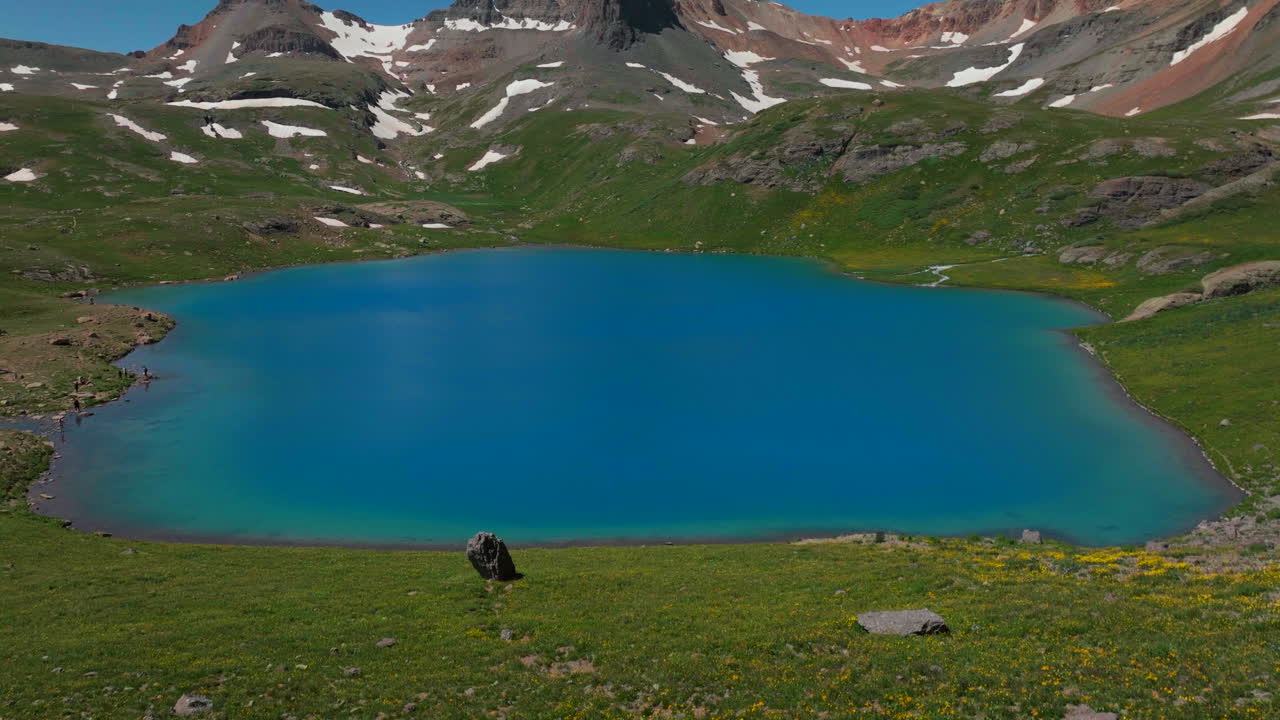 Luftfoto fra drone: Filmisk sceneri af dybblå himmel over den betagende Ice Lake Basin, Island Lake, Silverton, Colorado. Fantastisk, himmelsk og drømmende grøn sommer med vilde blomster i Rocky Mountains, hvor smeltende sne afslører Tellurides 14er-toppe.