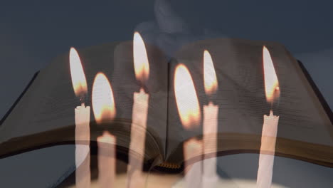 composite video of burning candles over woman hands with rosary praying against open bible