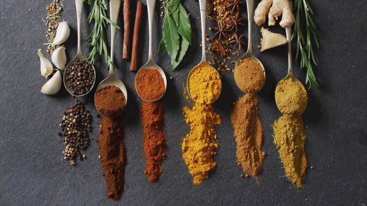 Video of spoons with diverse seasonings and herbs lying on grey background