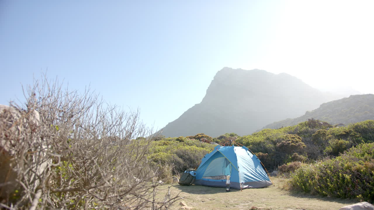 Camping in blue tent, woman enjoying mountain hike in scenic wilderness, copy space