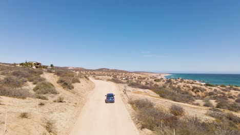 Antena:-Conducción-De-Automóviles-En-Un-Sinuoso-Camino-De-Tierra-En-La-Costa-Mexicana,-Toma-De-Seguimiento