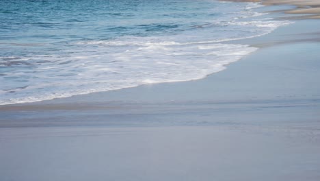 waves roll slowly on the sandy beach