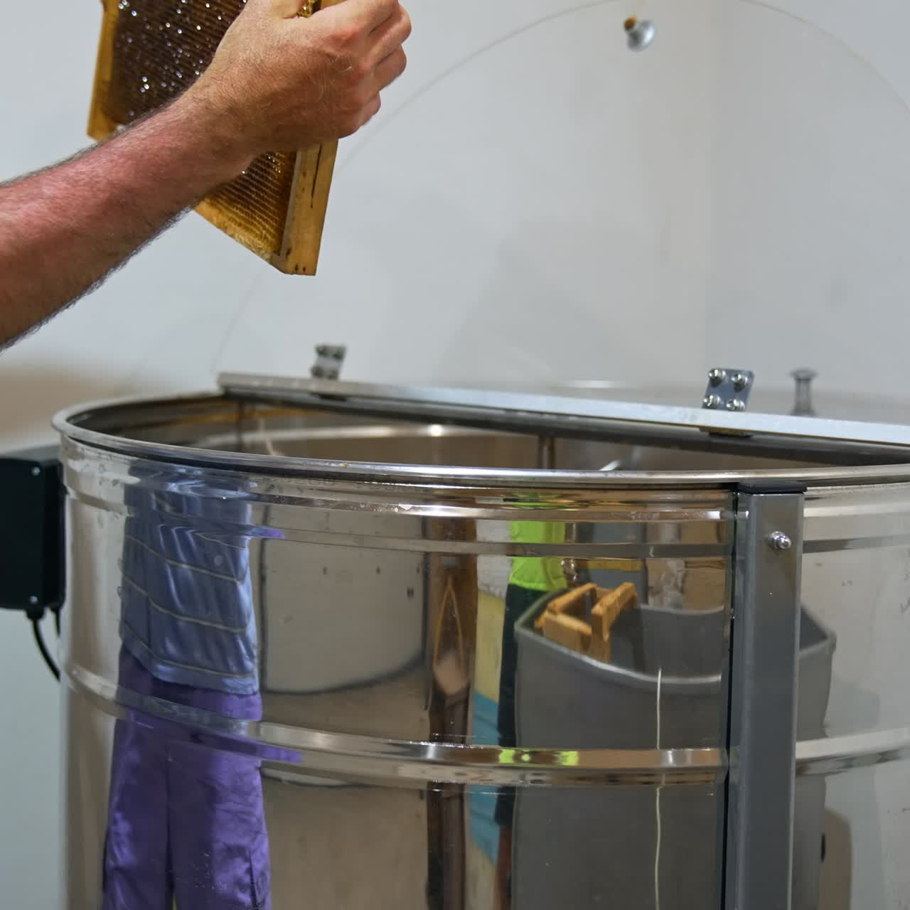 Shiny silver metal barrel where beekeeper loads the wooden frames. Centrifuge is getting ready for honey extraction