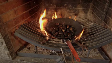 Cocinar-Castañas-Con-Una-Sartén-En-Una-Chimenea,-De-Forma-Tradicional,-Cámara-Orbital.