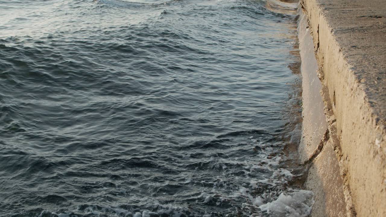 agua de mar subiendo y bajando, rompiendo olas en el muelle de cemento furiosamente en cámara lenta