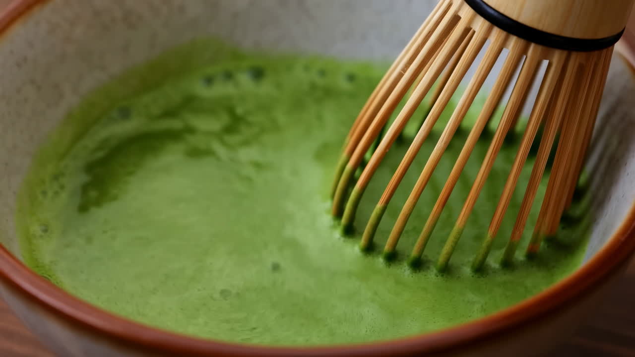Chá Matcha Batido Brilhante em Tigela de Cerâmica, Batedor de Bambu Criando Textura Cremosa e Espumosa, Pó Verde Vibrante