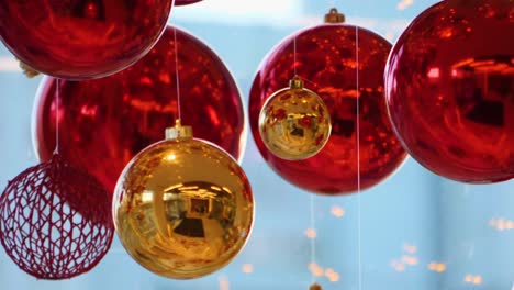 christmas and new year decoration. christmas big red balls on  background of luminous lanterns and gold garlands. holiday background. blinking garland. red baubles with lights twinkling close up.