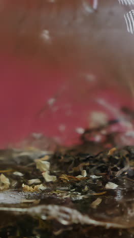 pouring hot water over tea leaves in a glass cup
