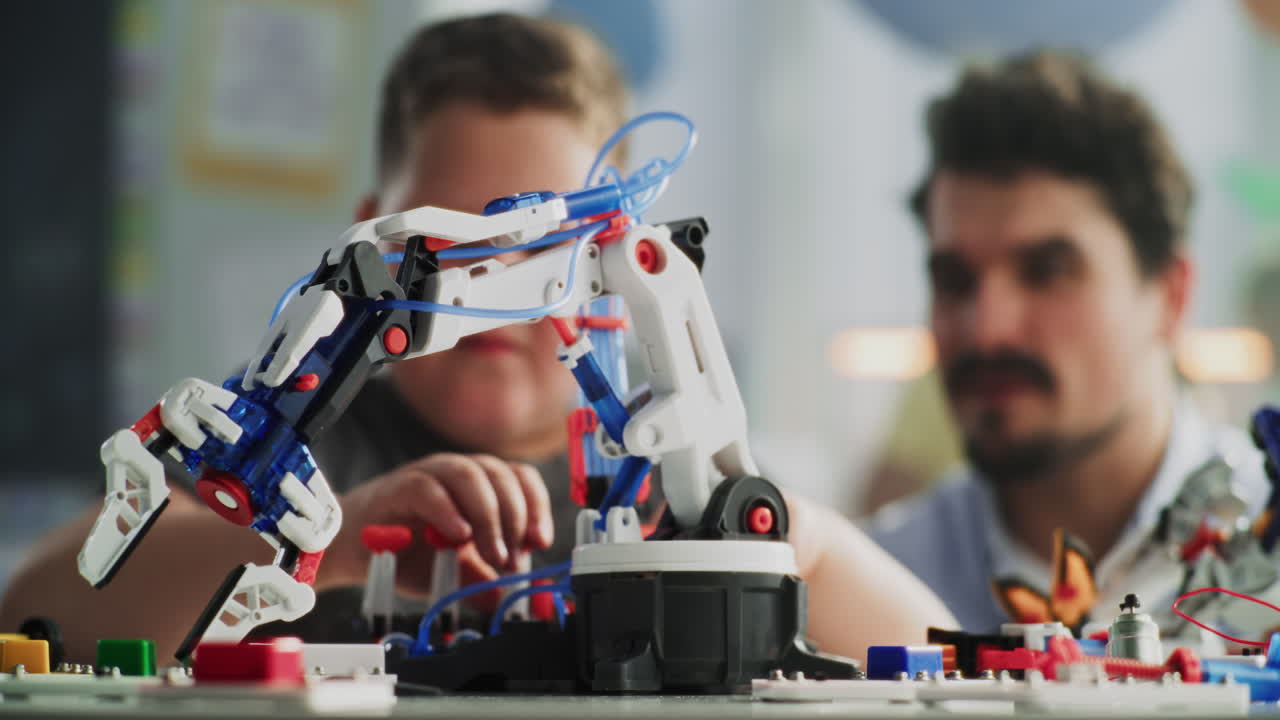 Elementary School Boy Studying Model of Innovative Robotic Arm Teacher Helping Smart Young Student