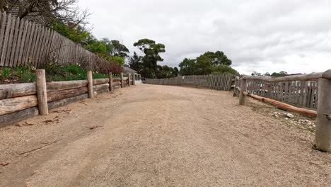 a dirt pathway with wooden fences