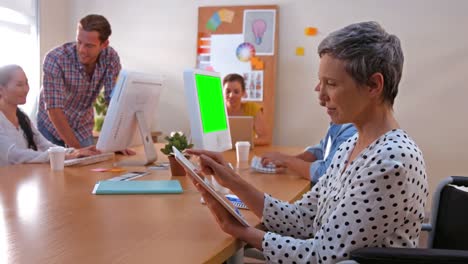Mujer-De-Negocios-Usando-Una-Tableta-Mientras-Sus-Colegas-Trabajan-En-Una-Computadora-Portátil