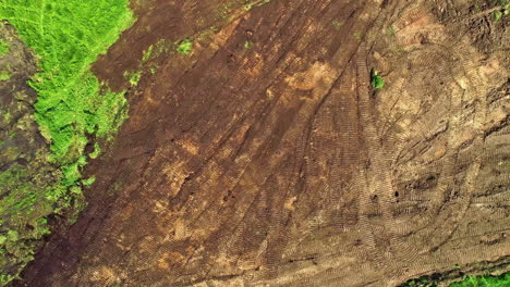 Top-view-of-tractor-machine-plowing-ground-on-farm-field-of-dust-trails-behind-preparing-soil-for-planting-new-crop-at-daytime