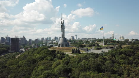 4k aerial drone footage of motherland monument of ukraine along with the huge ukrainian flag on a cloudy summer day