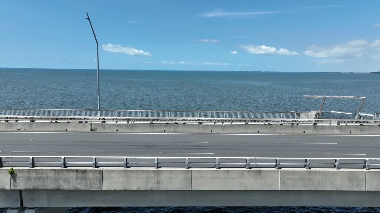테드 스무트 메모리얼 브릿지 (ted smoot memorial bridge) 의 트래킹 에 드론이 있습니다. 모레톤 베이 (moreton bay) 의 물 위에 있는 카메라와 배경으로 열린 바다, 고 은 날의 한낮에 찍은 사진입니다.