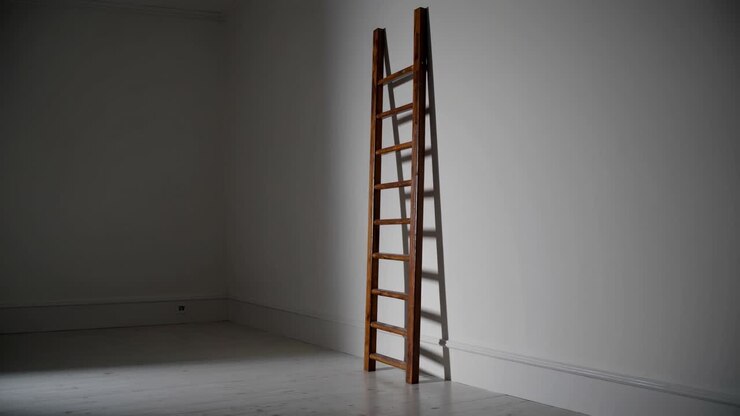 A minimalist video scene featuring a wooden ladder leaning against a white wall, captured from a low