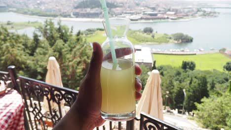 mano sosteniendo una bebida refrescante con vistas a la ciudad