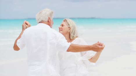 una pareja caucásica senior compartiendo un beso en una playa tropical.
