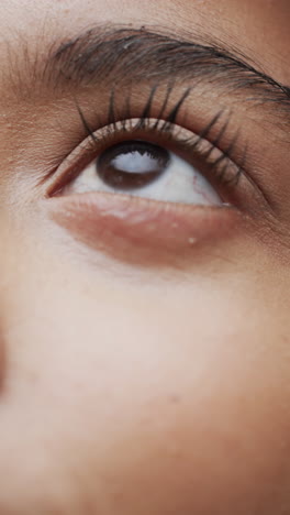 vertical video of eye of biracial woman with dark hair, slow motion