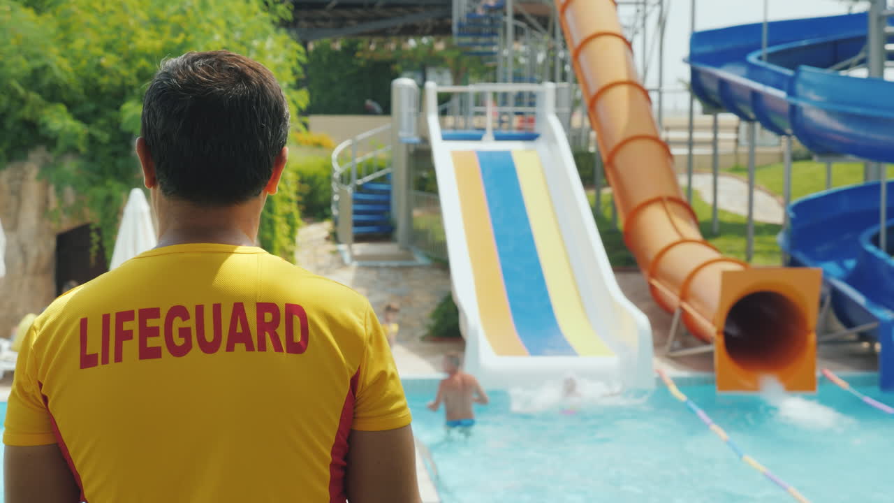 vista trasera - el salvador observa a la gente en los toboganes de agua trabajando en el parque acuático