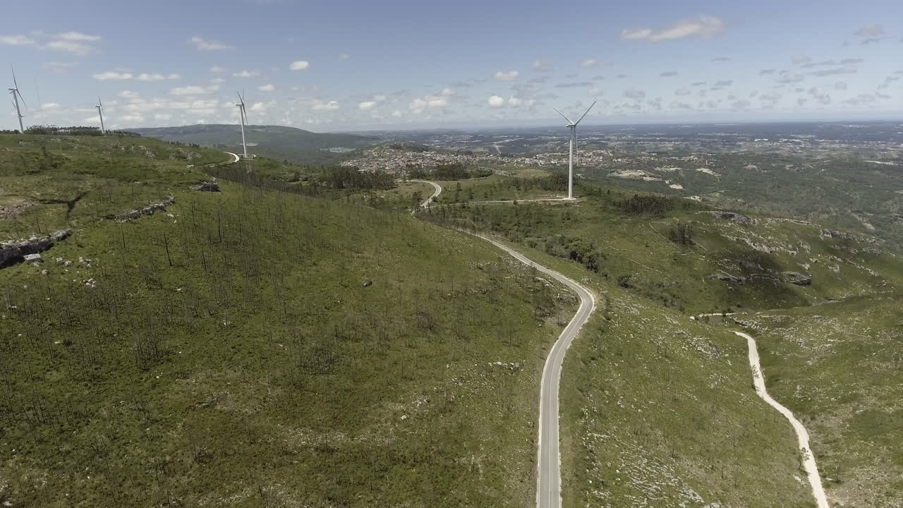 turbinas de viento girando en las exuberantes montañas en reguengo do fetal, batalha, portugal en un día soleado - disparo de drone ascendente