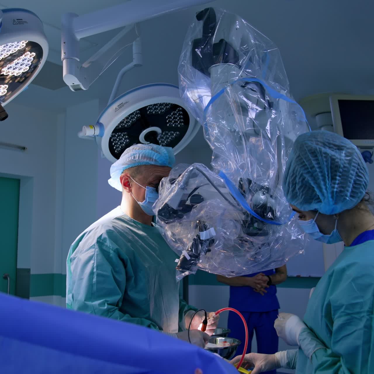 Professional neurosurgeon comes up to a microscope. Doctor holds surgical devices in both hands. Female nurse using syringe