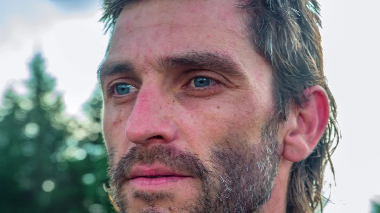 toma en cámara lenta de un hombre mirando seriamente al frente con árboles en el fondo