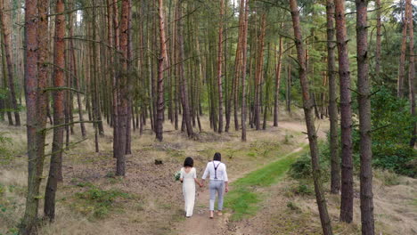 newlywed couple walking barefoot on a forest road,throwing the bouquet