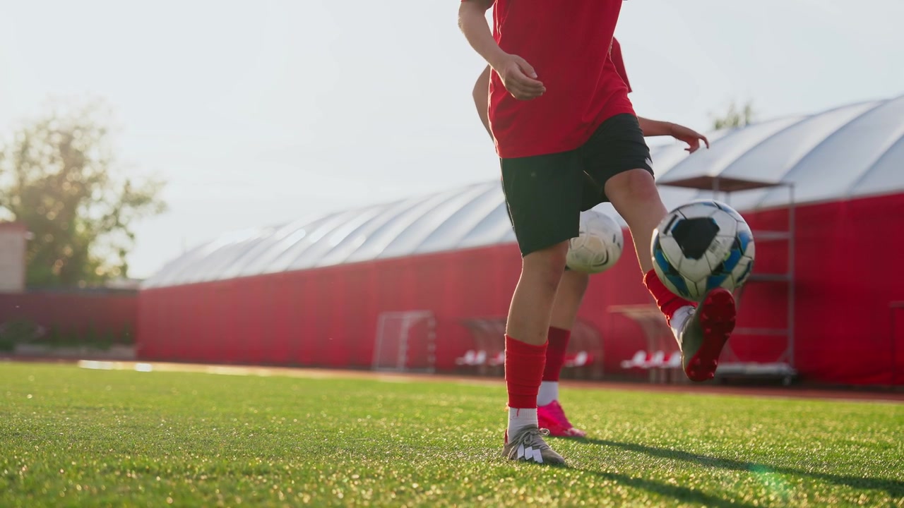Dua Pemain Sepak Bola Muda Berlatih Mengontrol Bola di Lapangan