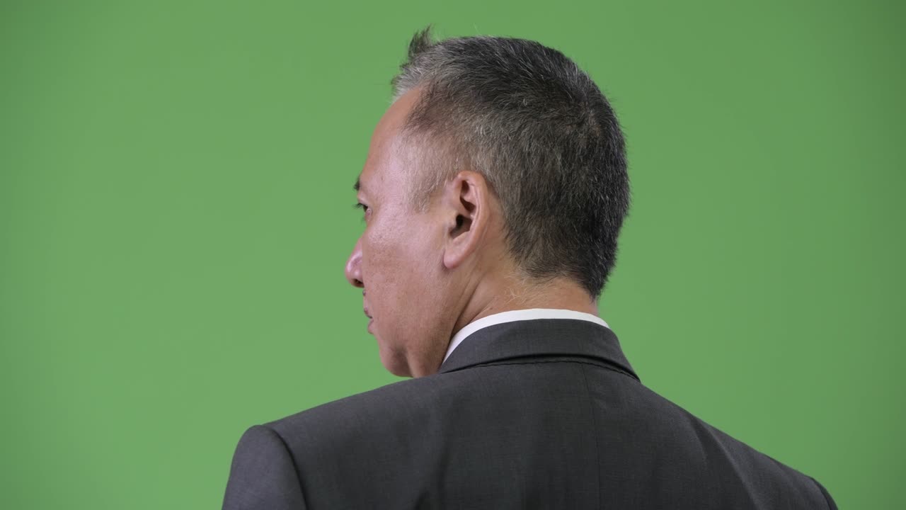 зрелый японский бизнесмен смотрит через плечо