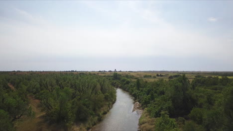 Toma-Aérea-Descendente-Sobre-Un-Río-Ventoso-En-El-Campo