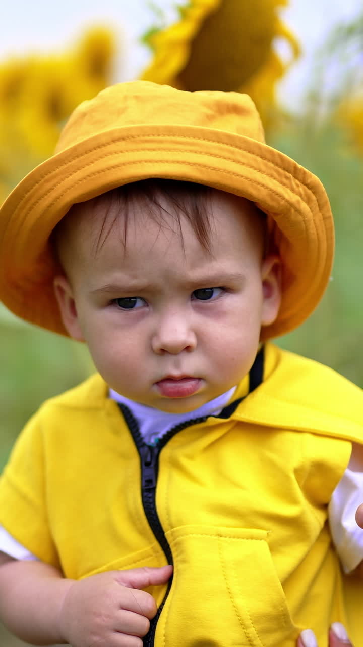 Bayi Berjaket dan Bertopi Kuning di Ladang Bunga Matahari