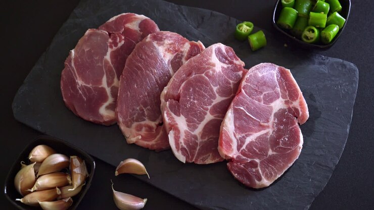 Daging babi segar mentah atau daging babi kerah di atas papan dengan bahan-bahan untuk diasinkan