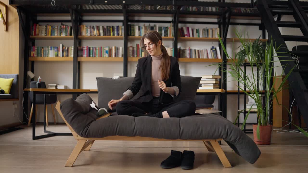 Woman Stretching on a Sofa in a Modern Home Office