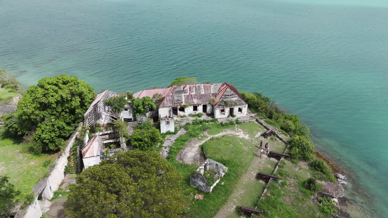 Fort James Antigua by the sea shows a weathered, abandoned building surrounded by lush greenery
