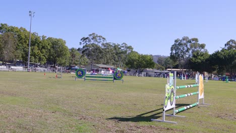 horse and rider jumping over obstacles in field