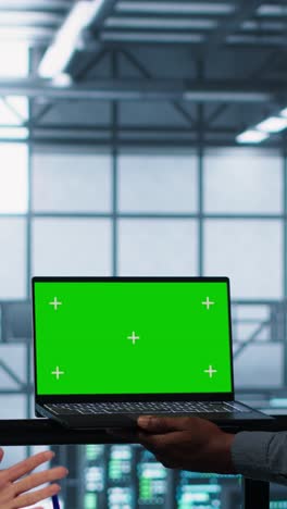 vertical video technicians in data center using green screen mockup laptop