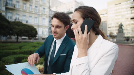 handsome business man showing data in documents to beautiful woman in street.