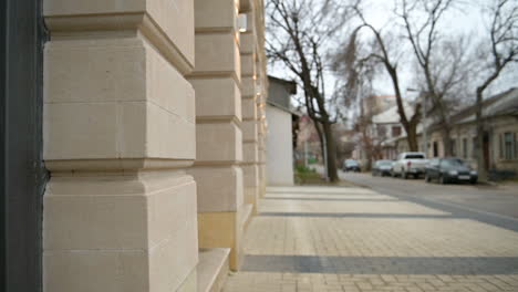 side view of an unrecognizable blind man holding a walking stick and entering a building