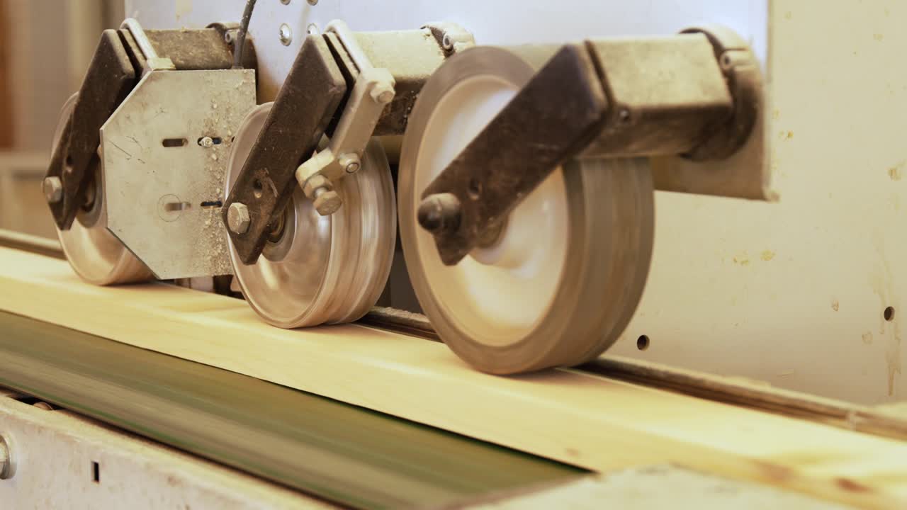 A close-up on an automated production line. Industrial wheels guide finished wooden planks along a conveyor system, showcasing the smooth workflow of a modern timber factory