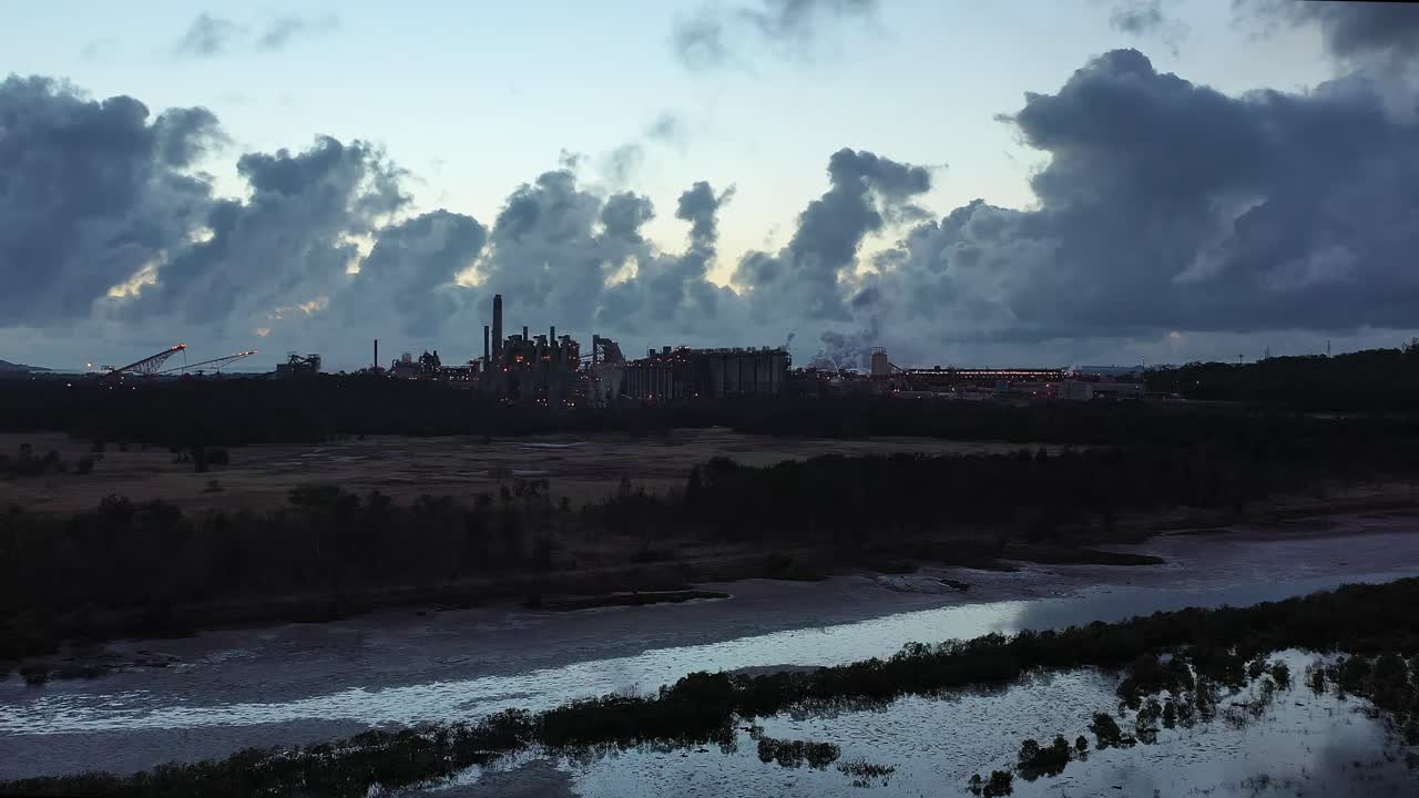 disparo de drones volando hacia la fábrica de carbón y metal al amanecer, grandes pilas de humo operando