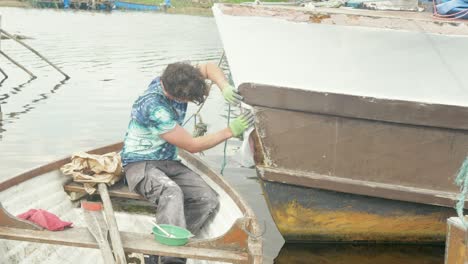 Un-Carpintero-Fija-Una-Estera-De-Fibra-De-Vidrio-En-La-Proa-De-Un-Barco-De-Madera