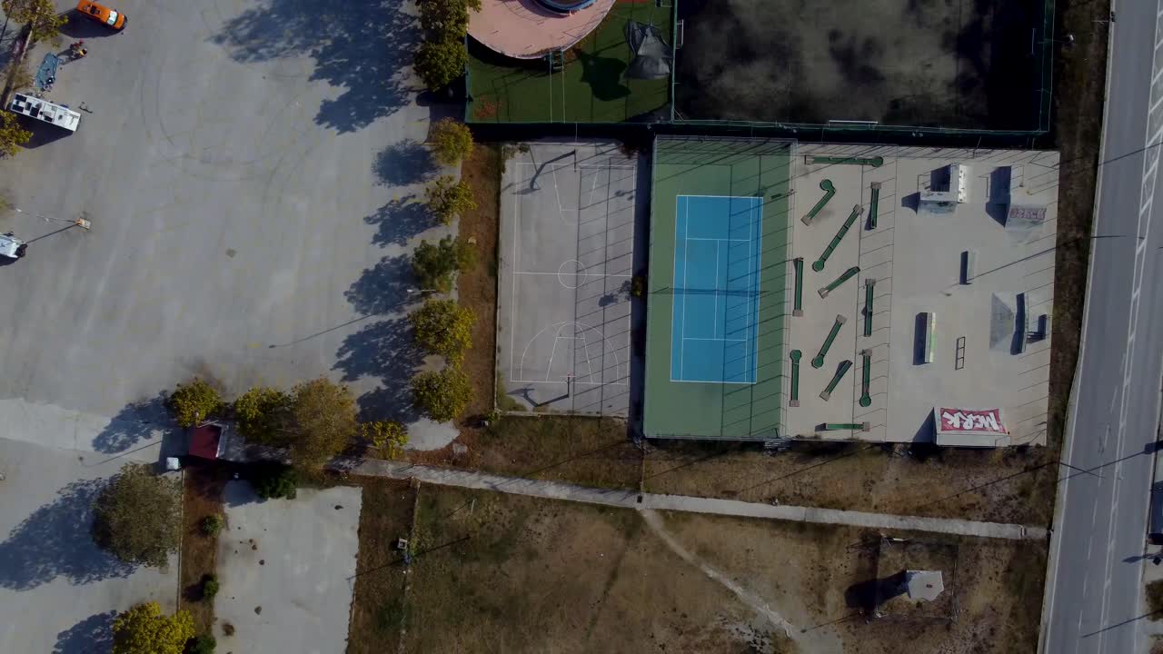 Aerial top down pan over outdoor sports facilities with tennis, basketball, mini golf and skate park