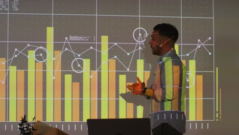 Male-Teacher-Giving-Maths-Or-Science-Lesson-In-School-Standing-At-The-Front-Of-Class-With-Projection-Of-Graph-3