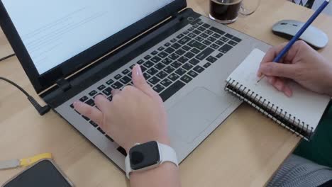 writer or creator drafting ideas in a notebook before typing on a laptop