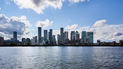 the modern skyline of canary wharf in london docklands view across the river thames on a summers day showing all the new skyscrapers of this cluster